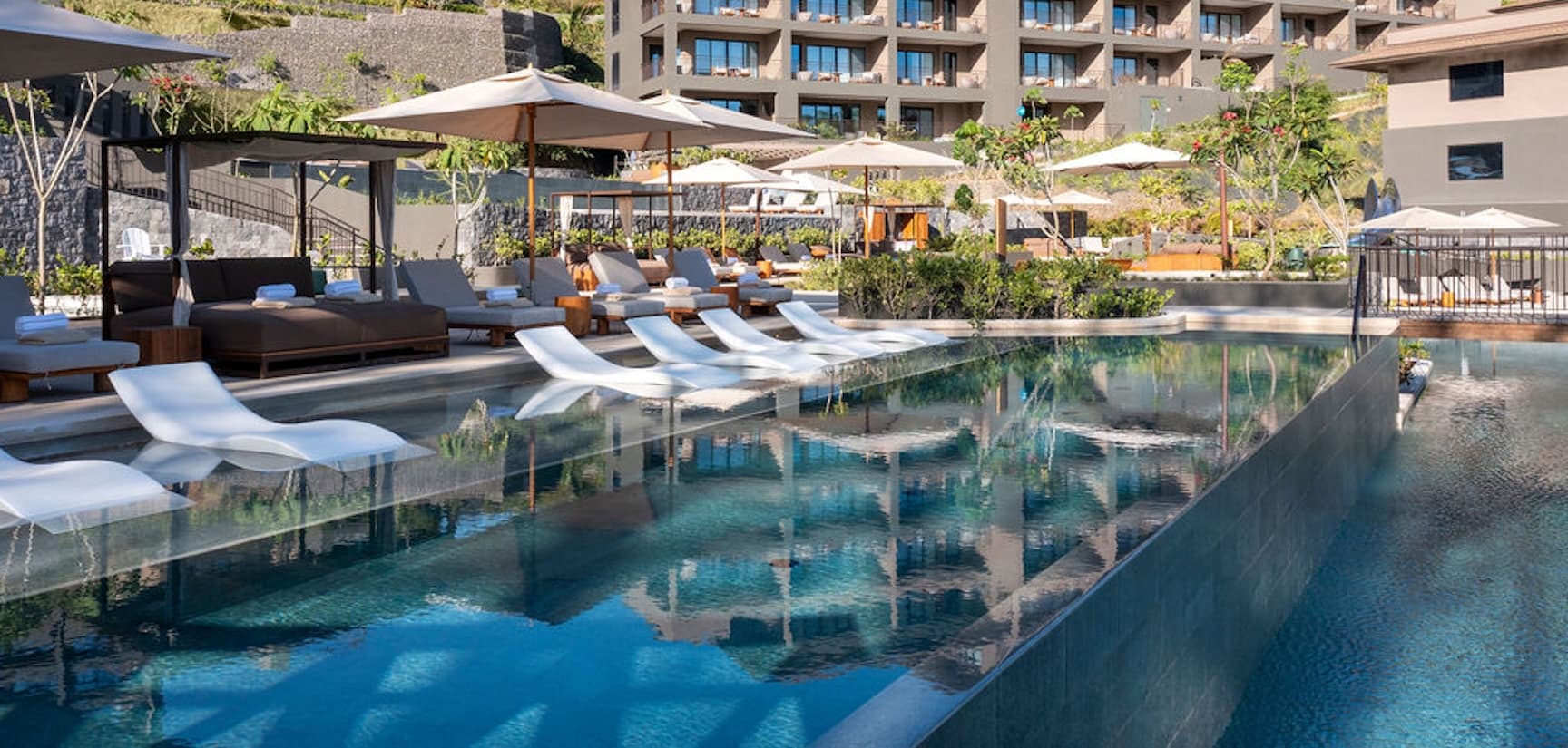 Ocean view from an infinity pool with the water’s edge blending into the horizon, palm trees nearby, and the Gulf of Papagayo stretching into the distance.