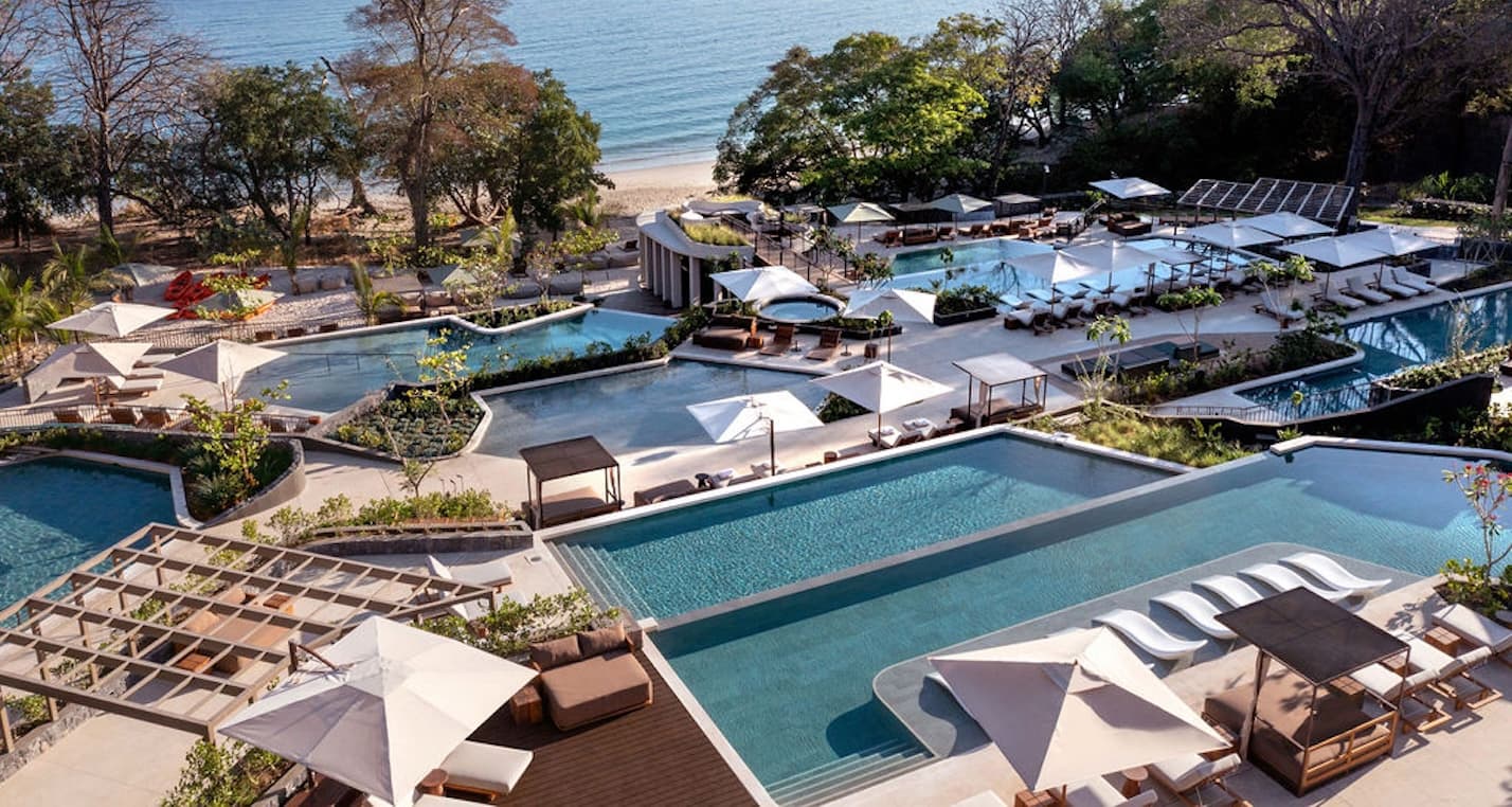 Wide aerial view of the Waldorf Astoria Punta Cacique Costa Rica hotel's terraced pools, cabana's and lounge chairs with ocean views of the Gulf of Papagayo.